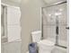 A contemporary bathroom features a toilet, frameless glass shower, stylish lighting, and a wavy mirror at 222 Rippling Nw Dr, Marietta, GA 30064
