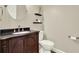 Elegant powder room with dark wood vanity, granite countertop, and decorative floating shelves above toilet at 222 Rippling Nw Dr, Marietta, GA 30064