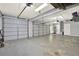 Large garage with three white garage doors, a gray floor, and additional space with shelves and cabinets at 222 Rippling Nw Dr, Marietta, GA 30064