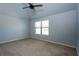A well-lit, empty bedroom with a ceiling fan, window, and neutral carpet at 3228 Trinity Mill Cir, Dacula, GA 30019