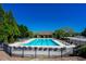 A fenced community pool features lounge chairs and is surrounded by lush trees at 3228 Trinity Mill Cir, Dacula, GA 30019