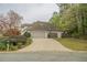 Charming home showcasing a two-car garage and a long driveway surrounded by mature trees and shrubbery at 5713 Brynwood Nw Cir, Acworth, GA 30101