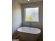Bathroom featuring a modern freestanding tub with chrome fixtures and natural light at 390 River Walk Farm Parkway Lot 47, Covington, GA 30014