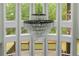 Close up on a chandelier hanging in a living room with tall windows and hardwood floors at 6048 Golf View Xing, Locust Grove, GA 30248
