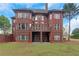 Back exterior featuring a brick home with multiple windows and a large yard at 6048 Golf View Xing, Locust Grove, GA 30248