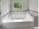 A luxurious white bathtub with marble tile and a window view, perfect for relaxation in this modern bathroom at 6367 Deshong Dr, Lithonia, GA 30058