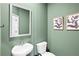 Modern half bathroom featuring a white sink, toilet, olive green walls, and framed artwork at 11569 Kimberly Way # 26, Hampton, GA 30228