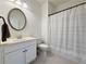 Bright bathroom with a white vanity, round mirror, and a shower with a striped curtain at 5515 Allegre Pl, Cumming, GA 30028