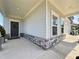 Inviting front porch with stone accents, a dark front door with a wreath, and gray siding at 5515 Allegre Pl, Cumming, GA 30028