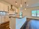 Kitchen island with granite countertops, a stainless steel sink, and modern pendant lighting at 5515 Allegre Pl, Cumming, GA 30028