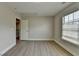 Bedroom with light gray walls, hard surface floors, window, and entry way to another room at 5976 Princeton Run Trl, Tucker, GA 30084