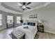 Comfortable main bedroom with tray ceiling, ceiling fan, lots of light, and modern decor at 5976 Princeton Run Trl, Tucker, GA 30084