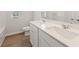 Bright bathroom with double sinks, white cabinets and wood-look flooring with a view of a tub and shower at 7099 Brushwood Bend (Lot 49), Lithonia, GA 30058