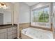 Bathroom showcasing a soaking tub, vanity with granite countertops, drawers, and natural light at 1074 Fieldstone Dr, Canton, GA 30114