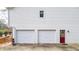 Two-car garage with white doors and a red side door, showcasing ample parking and access at 1074 Fieldstone Dr, Canton, GA 30114