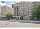 Street view of The Aramore building showing brick and stone, balconies, mature trees, and pedestrian-friendly street at 2277 Peachtree Ne Rd # 310, Atlanta, GA 30309