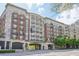 Street-level view of the Aramore building featuring a brick facade, covered entryway, street-level retail and mature trees at 2277 Peachtree Ne Rd # 310, Atlanta, GA 30309