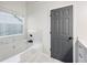 Bright bathroom featuring a bathtub, marble backsplash, and a large window at 5789 Star Flower Dr, Ellenwood, GA 30294