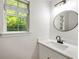 Modern bathroom featuring a large window, stylish light fixture, and sleek, round mirror at 5789 Star Flower Dr, Ellenwood, GA 30294