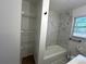 This bathroom features a tub with stylish marble-style tile and convenient built-in shelving at 185 Maple Wood Dr, Lawrenceville, GA 30046