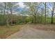 View of the cracked concrete driveway leading to the house surrounded by lush trees at 5026 Daniel Mill Rd, Winston, GA 30187