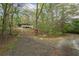 A home surrounded by trees, seen from the gravel driveway and entrance to the property at 5026 Daniel Mill Rd, Winston, GA 30187