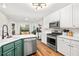 Bright kitchen with stainless steel appliances, white cabinets, green island with quartz countertops, and eat-in nook at 500 Katherines Cv, Mcdonough, GA 30253