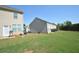 A large grassy backyard with a grill, a small patio, and beige siding at 5829 Taka Ln, Lithonia, GA 30038