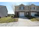 A townhome with a one-car garage, brick accents, light beige siding, and a driveway with landscaped lawn at 5829 Taka Ln, Lithonia, GA 30038