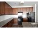 Well-equipped kitchen with black appliances, granite countertops, and wood cabinets at 5829 Taka Ln, Lithonia, GA 30038