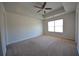 Spacious main bedroom featuring neutral carpeting, ceiling fan, and ample natural light from the window at 5829 Taka Ln, Lithonia, GA 30038