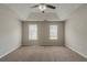 Spacious bedroom with plush carpet, two windows, and a modern ceiling fan at 6205 Leverett Dr, Lithonia, GA 30038