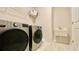 Modern laundry room with front-load washer and dryer, tiled floor, and sink at 1835 Wellston Dr, Lawrenceville, GA 30043