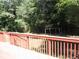 View of the backyard from the spacious, red wooden deck, with a playground visible and surrounded by dense bamboo trees at 2107 Briarwood Ct, Snellville, GA 30078