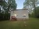 Rear view of the house showing vinyl siding, small deck and access stairs to backyard with large trees at 691 Aberdeen Dr, Stone Mountain, GA 30083