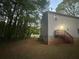 Rear view of a two-story house with a deck and stairs, surrounded by lush trees at 691 Aberdeen Dr, Stone Mountain, GA 30083