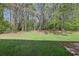 A grassy backyard featuring a brick patio and privacy provided by mature trees at 3479 Portsmouth Cir, Lithonia, GA 30038