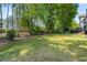 Spacious backyard featuring a lush lawn, iron fence, mature trees and a deck with stairs at 4862 Tarry Post Ln, Suwanee, GA 30024