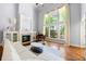 Bright living room with fireplace, hardwood floors, piano, and large window offering a view of the outdoors at 4862 Tarry Post Ln, Suwanee, GA 30024
