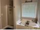 Elegant bathroom featuring a soaking tub with jets, shower, and modern fixtures at 220 Cameron Ways, Covington, GA 30016