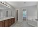 Bright bathroom with a double sink vanity, soaking tub, and gray tile flooring at 7228 Silverleaf Cir, Fairburn, GA 30213