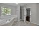 Bright bathroom showcasing a soaking tub, a glass-enclosed shower, and a view to the trees outside at 7228 Silverleaf Cir, Fairburn, GA 30213