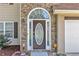 Charming front entrance with stone archway, decorative glass door, and white garage door at 7228 Silverleaf Cir, Fairburn, GA 30213
