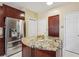 A kitchen island with granite countertops, stainless steel refrigerator, and wooden cabinetry offers ample storage at 1490 Rivershyre Pkwy, Lawrenceville, GA 30043