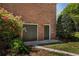 Brick home's exterior features a door leading to the basement and a garage door, surrounded by green foliage and bright pink azalea bushes at 200 Sugar Mill Ln, Canton, GA 30115