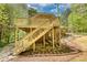 Two-story wooden deck with staircase leading to backyard with lush landscaping and rocks at 1660 Weems Rd, Locust Grove, GA 30248