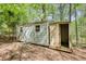 Outbuilding with siding, a door, and windows, set among trees, providing additional storage space at 1660 Weems Rd, Locust Grove, GA 30248