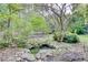 Landscaping area featuring a stone-lined water feature with mature shrubs and trees at 1660 Weems Rd, Locust Grove, GA 30248