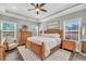Bright main bedroom featuring a tray ceiling, wood furniture, and a cozy sitting area by the windows at 220 Alcovy Reserve Way, Covington, GA 30014