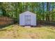 The white storage shed is nestled in a grassy backyard, bordered by a wooden fence at 101 Valleydale Dr, Stockbridge, GA 30281